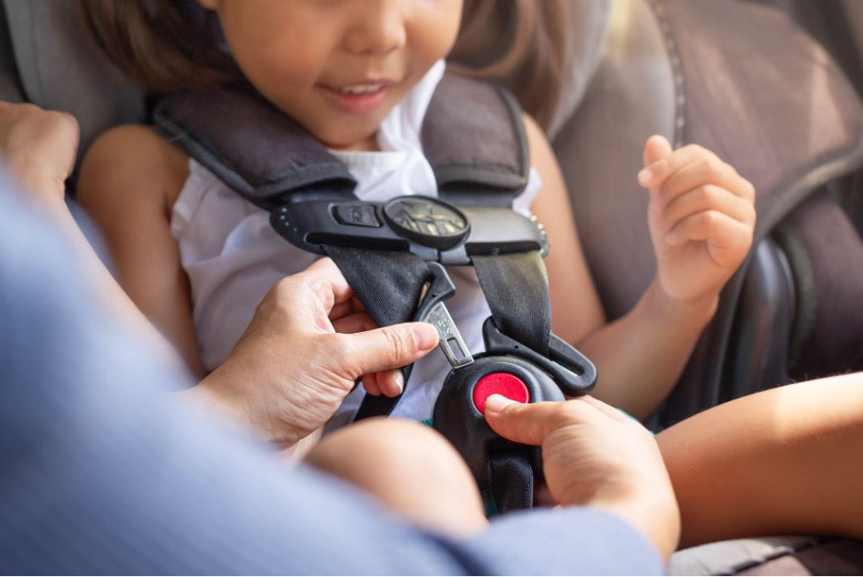 Toddler being buckled in a car seat